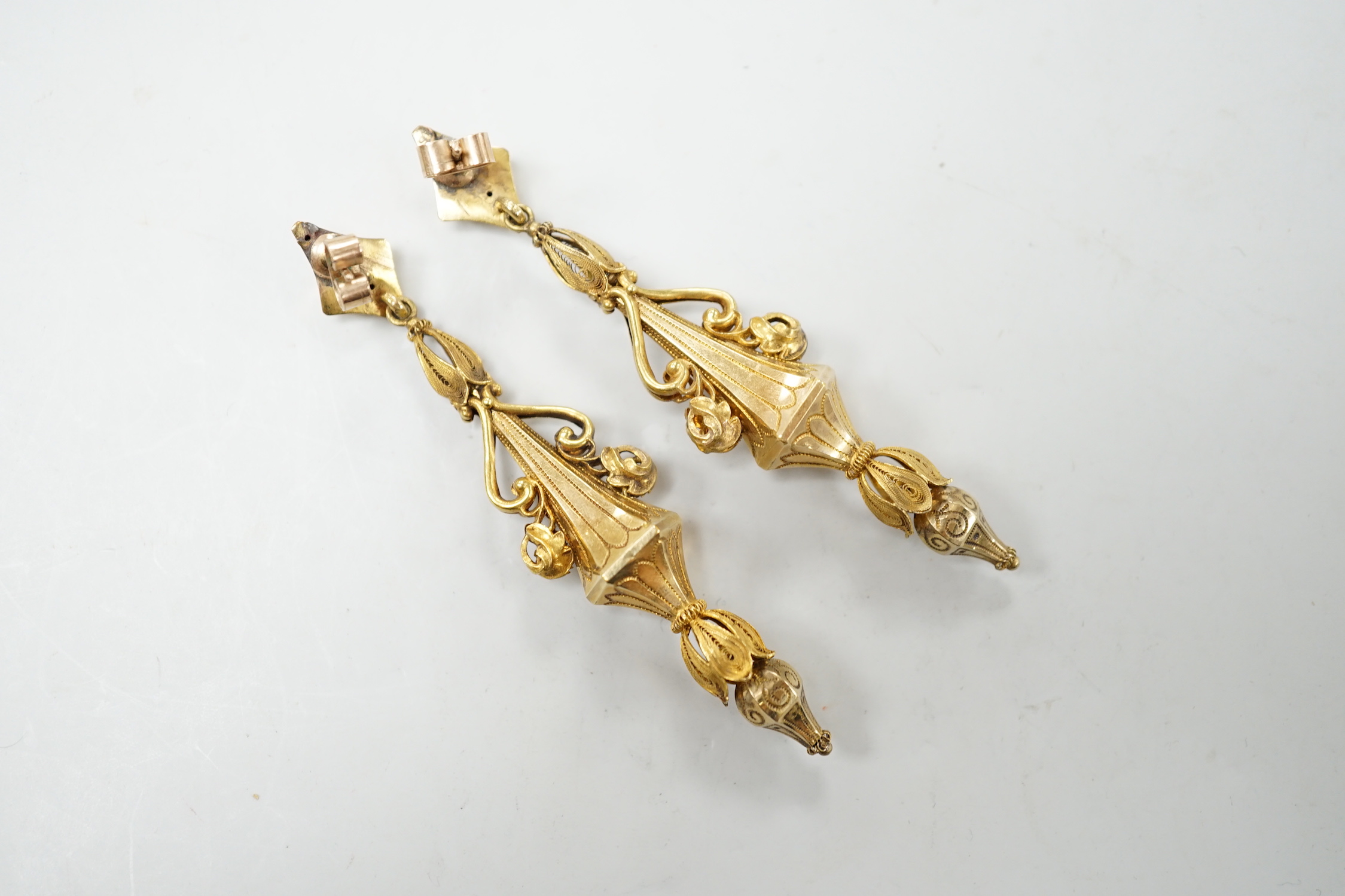 A pair of early 20th century yellow metal drop earrings, with scroll decoration, (later fittings?), 81mm, gross weight 10 grams.